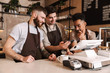 © Drobot Dean - Three cheerful men baristas standing behind the counter