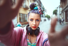 Playful Cool Funky Hipster Young Girl With Headphones And Crazy Hair Taking Selfie On Street