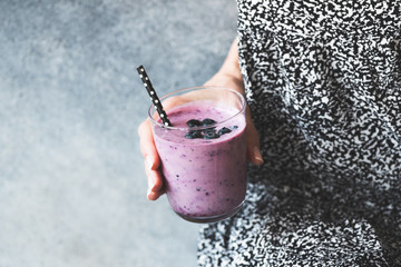 Wall Mural - Glass of blueberry smoothie in woman's hand. Clean eating, dieting, detox and weight loss concept