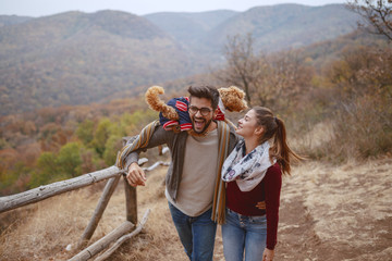 cute multicultural couple dressed casual hugging and taking a walk in nature with their dog. man hol