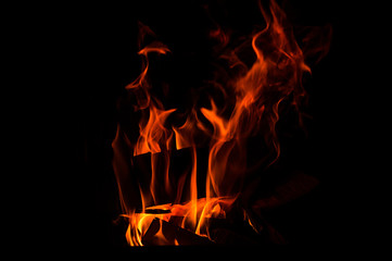 Close up. Abstrack background. Burning wood in the fireplace. Red-orange flames meander in the darkness. Copy space.