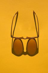 Poster - Sunglasses with long shadow on a brignt summer yellow background