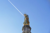 Fototapeta Londyn - Beautiful golden statue of Blessed Virgin Mary high in the blue sky and sign  sky 