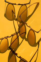 Poster - Sunglasses with long shadow on a brignt summer yellow background