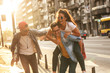 © BalanceFormCreative - Group of friends hangout at the city street.They embrace each other and laughing.One man carrying female friend on his back.