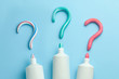 Question mark from toothpaste. Concept of choosing good toothpaste for teeth whitening. Tube of colored toothpaste on blue background. Copy space for text.