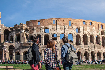 Wall Mural - Three happy young friends tourists in front of colosseum in rome