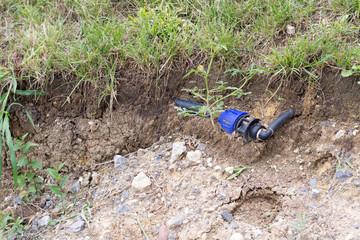 Black and blue installation pipe visible in the soil under the green grass surface