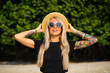 © Artem Markin - Beautiful blonde is smiling and looking at the morning sea. Holds a hat with his hands with tattoos. Travel to Thailand.