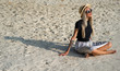 © Artem Markin - A girl in a straw hat sits on the morning beach. Modern girl on vacation