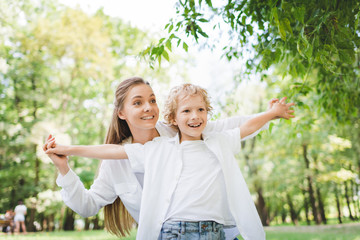 Wall Mural - beautiful happy mother holding hands with adorable son in park