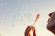 © Photocreo Bednarek - Young woman blowing bubbles to the sky at sunset.