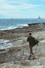 Wall Mural - man walking by rocky beach in windy day summer vacation. enjoy sea view