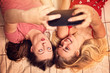 © ambrozinio - two young girls are taking a photo  by phone
