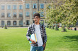 © Oleksandr - Portrait of a young African American student black man the background of college. Smiling teenage male mixed race keeps books standing near the university.