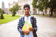 © Oleksandr - Portrait of a young African American student black man the background of college. Smiling teenage male mixed race keeps books standing near the university.