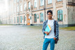 © Oleksandr - Portrait of a young African American student black man the background of college. Smiling teenage male mixed race keeps books standing near the university.