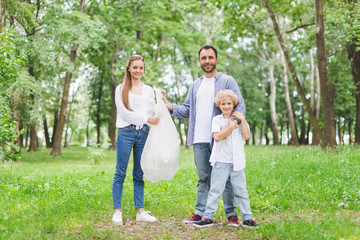 Wall Mural - father, mother and son with garbage in plastic bag in park