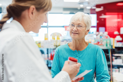 Fotomural Senior woman in pharmacy talking to the chemist or pharmacist