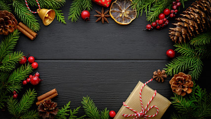 fir tree branches and christmas decorations on black wooden background with copy space