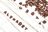 Fototapeta Tematy - dry cereal breakfast laid out with the word alphabet on a white wooden background.
