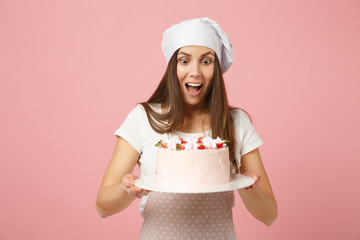 Wall Mural - Housewife female chef cook confectioner or baker in apron white t-shirt, toque chefs hat hold in hand cake on stand plate isolated on pink pastel background in studio. Mock up copy space food concept.