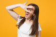 Portrait of cheerful peeping young woman in white casual clothes covering face with hand, keeping mouth open isolated on yellow orange wall background. People lifestyle concept. Mock up copy space.