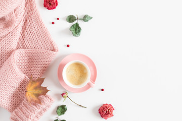 Autumn cozy composition. Dry yellow leaves, flowers, cup of coffee, pink knitted sweater on white background. Fall concept. Autumn background. Flat lay, top view, copy space