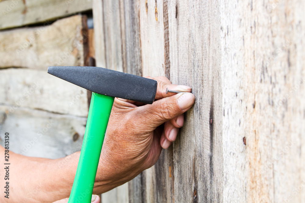To hammer a nail with a hammer. Older worker carpenter Stock Photo ...