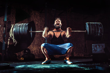 Wall Mural - Muscular bearded tattoed fitness man doing deadlift a barbell over his head in modern fitness center. Functional training. Snatch exercise