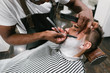 © Westend61 - Man getting his beard shaved with razor in barber shop