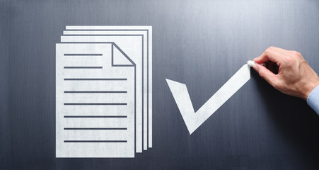 Wall Mural - Document management concept. Businessman drawing documents and check mark on chalkboard.