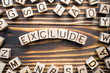 exclude wooden cubes with letters, to keep out or omit concept, around the cubes random letters, top view on wooden background