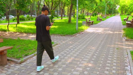 Poster - side view man wearing casual trendy clothes walking on the street in spring season. student using smartphone on the go