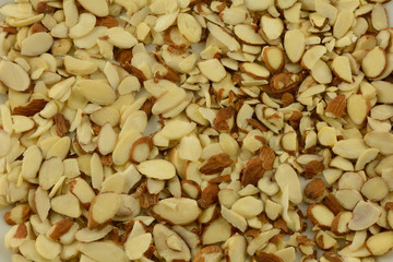 Background of heap of raw sliced almond nuts on white