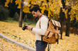 © JAKE JAKAB/ADDICTIVE STOCK - Side view of handsome young photographer standing in autumn park and watching pictures on camera