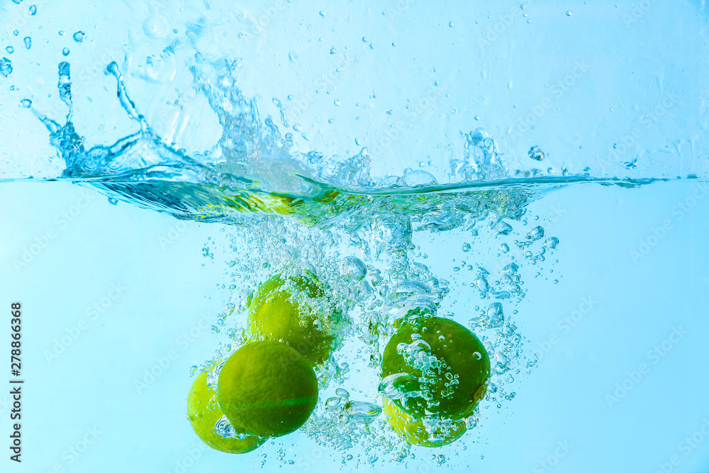 Falling of limes into water on light background