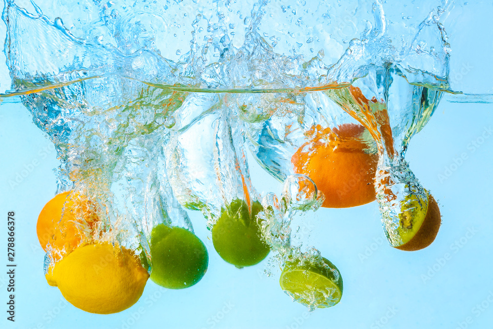 Falling of different fruits into water on light background