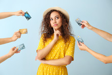 Thoughtful African-American Woman And Hands With Credit Cards On Color Background