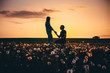 Silhouettes of a man making marriage proposal to his girlfriend on the spring meadow at sunset. Landscape with silhouette of lovers against colorful sky. Couple. People, relationship.