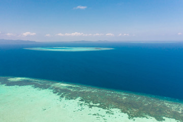 Atoll and blue sea, view from above. Seascape by day. Turquoise and blue sea water.