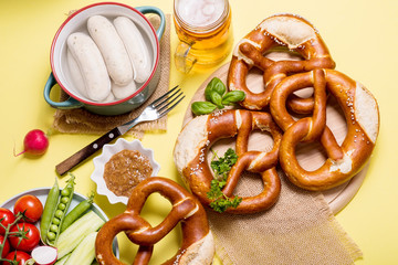 Wall Mural - Pretzels, white bavarian sausages, mustard and beer, german traditional food, oktoberfest on yellow background