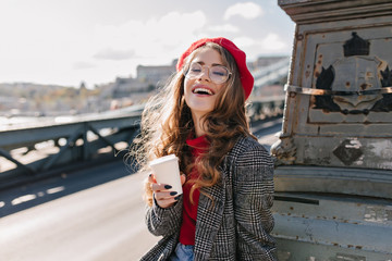 interested caucasian girl in vintage outfit drinking coffee during trip around europe. outdoor photo