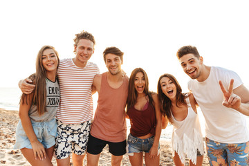 Poster - Group of happy friends standing at the beach together