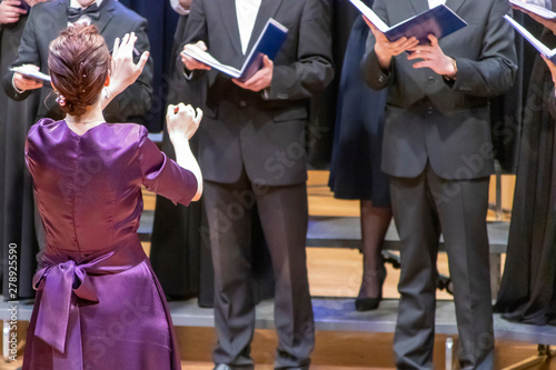 Fotografía A young girl in dress conducts a male choir