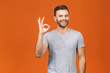 © denis_vermenko - Portrait of a cheerful young man showing okay gesture isolated on the orange background. Ok sign.