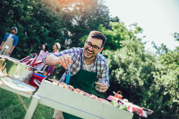 Handsome male preparing barbecue outdoors for friends