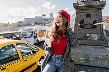 Wall Mural - stylish woman with cup of tea dreamy looking away in warm october day. attractive white girl in bere