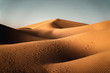 Düne in der Sahara Wüste mit Fussspuren von Dromedaren und Menschen mit bewölktem Himmel in Marokko