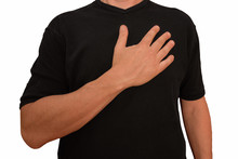 Guy Keeps Arm On Breast Near Heart With Palm. Gesture Of Man In Black T-shirt Isolated With No Face. Concept Of Honor And Patriotism